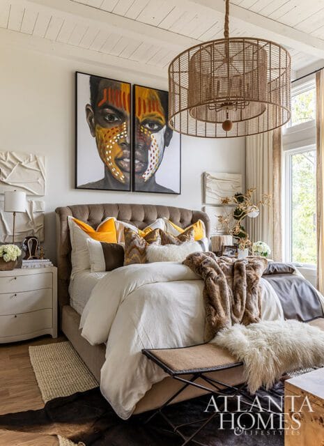 Bedroom with tufted headboard, white bedding, fur throw, and diptych portrait art.
