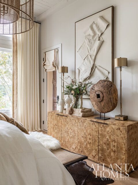 Bedroom with burl wood dresser, abstract wall art, and floor lamps.