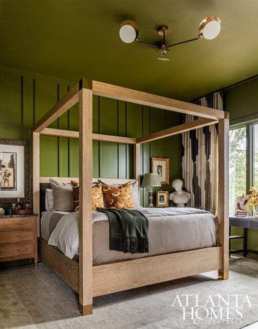 Bedroom with green paneled walls, a wooden four-poster bed, and a modern chandelier.
