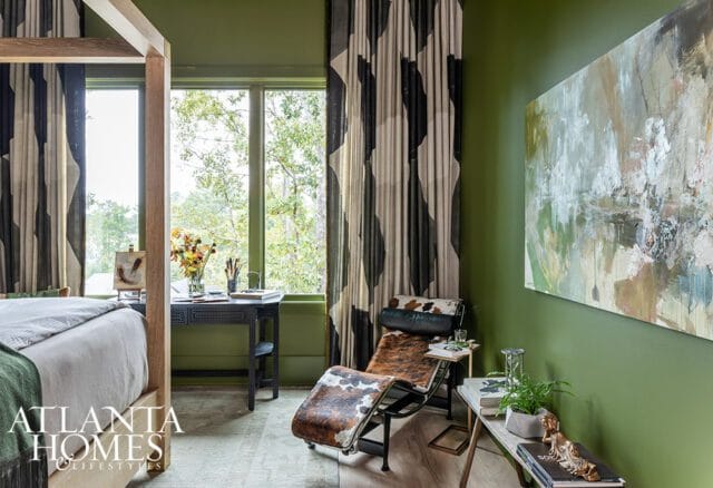 Green bedroom with a four-poster bed, abstract art, and a cowhide chaise lounge.
