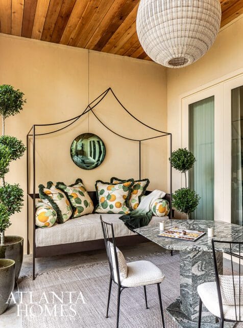 Outdoor seating area with striped sofa, orange-patterned pillows, and marble table.
