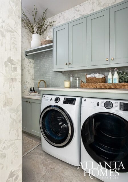 Laundry room with light blue cabinets, subway tile backsplash, and floral wallpaper.