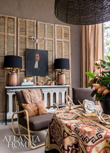 Living room with antique shutters, portrait, copper lamps, and patterned tablecloth