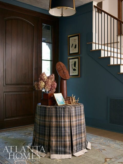 Entryway with dark wood door, plaid skirted table, and blue walls