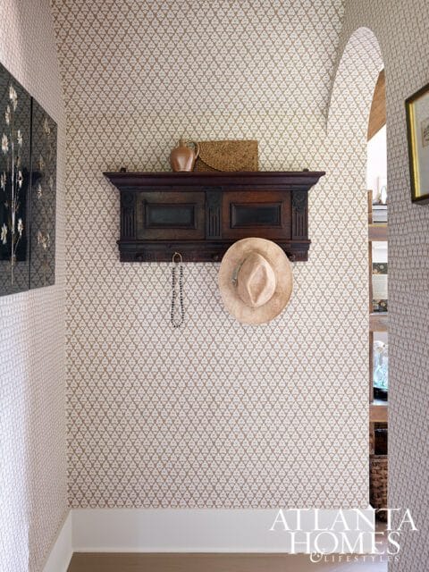 Hallway with patterned wallpaper, dark wood shelf with hat and vase, and Atlanta Homes & Lifestyles