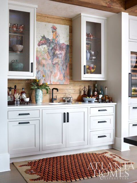 White bar with a painting of a rider on a horse, wood paneled wall, and tiger rug.