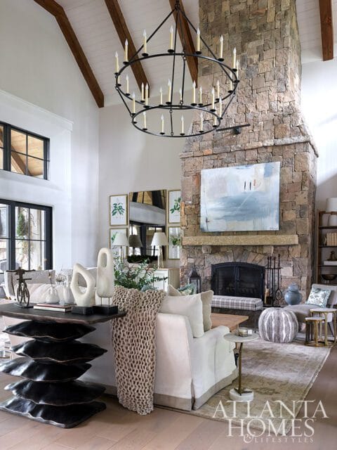 Living room with stone fireplace, large chandelier, and abstract art