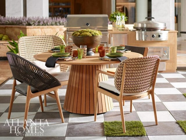 Round wood dining table with woven chairs and outdoor grill