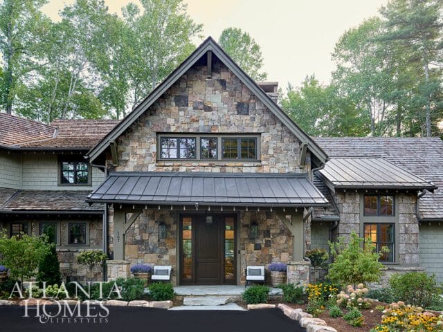 Stone and shingle house with metal roof and dark wood double doors.