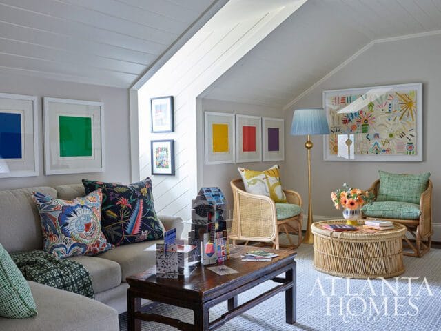 Living room with a sectional sofa, two rattan chairs, a wooden coffee table, and a round rattan coffee table. Artwork and colorful pillows add pops of color.