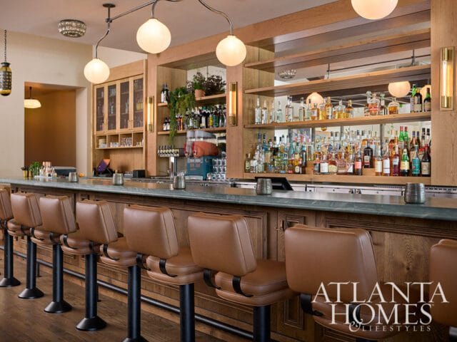 Bar area with brown leather stools, a marble countertop, and a well-stocked liquor shelf with mirrored backing.