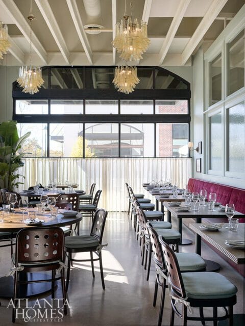 Restaurant dining room with dark wood chairs, light blue seat cushions, and a long red banquette seating area.