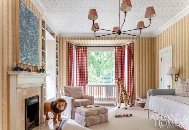 Children's room with striped wallpaper, a white crib, a stuffed lion, a giraffe toy, and a fireplace with a marble surround.