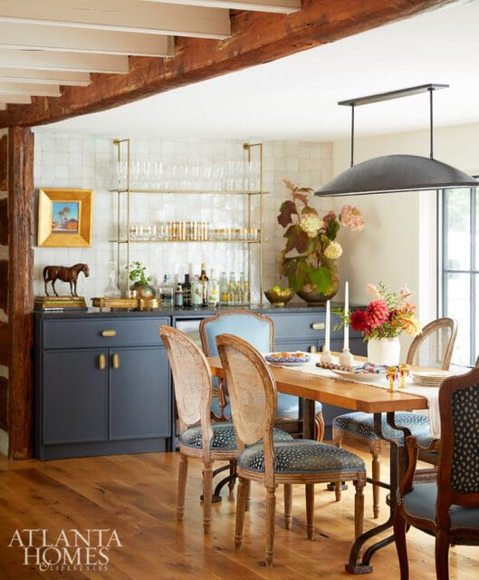 Dining room with dark blue cabinets, wood table, and upholstered chairs.
