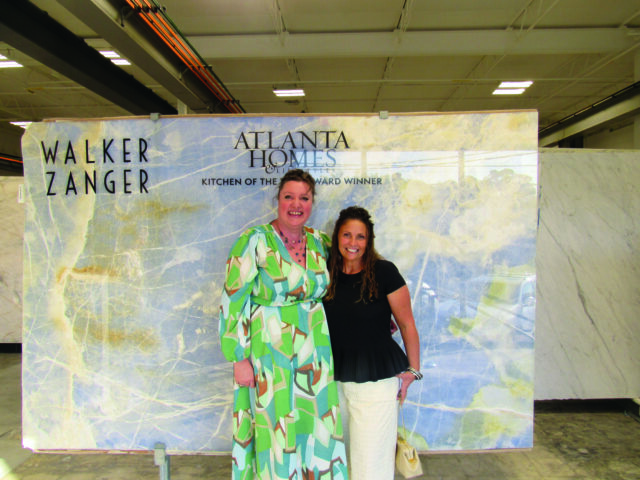 Two women stand in front of a large slab of blue and white marble with gold veining.