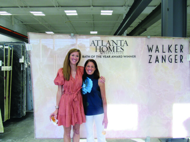 Two women stand in front of a large slab of pink marble with "Atlanta Homes & Lifestyles" and