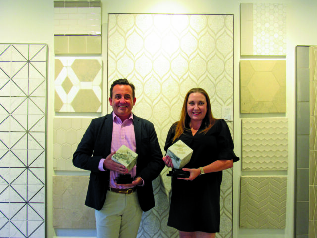 Man and woman holding awards in front of tile samples.