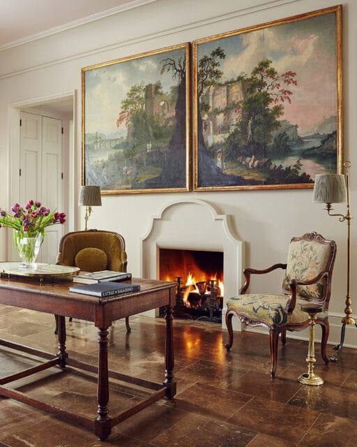 Living room with fireplace, two antique paintings, and antique furniture.