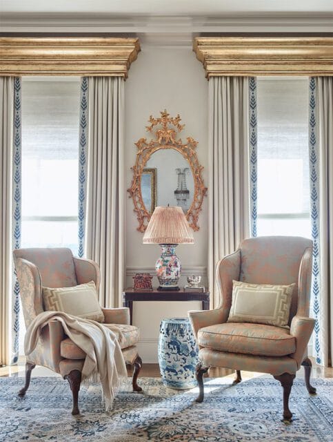 Two wingback chairs in a living room with patterned upholstery, ornate mirror, and blue and white