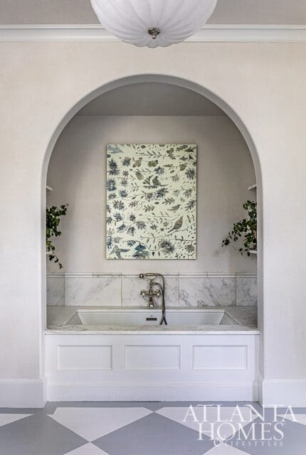 Bathroom with arched alcove, marble tub surround, floral artwork, and Atlanta Homes & Lifestyles