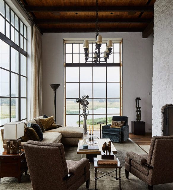 Living room with sectional sofa, two armchairs, and large windows overlooking a lake.