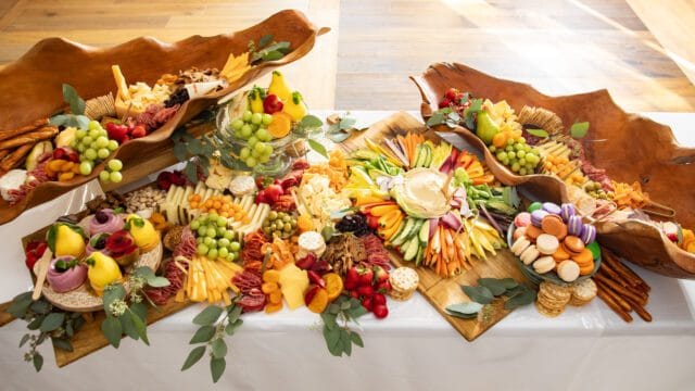 Platter with cheeses, meats, fruits, vegetables, macarons, and pretzels