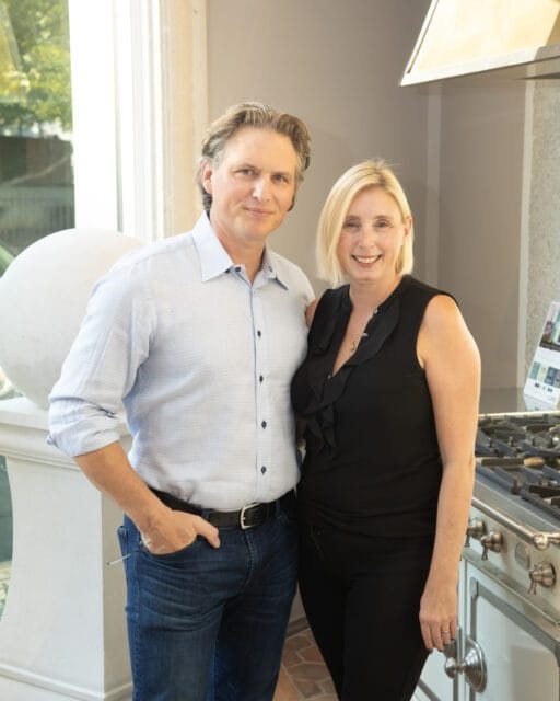 Man in blue shirt and woman in black top standing in kitchen