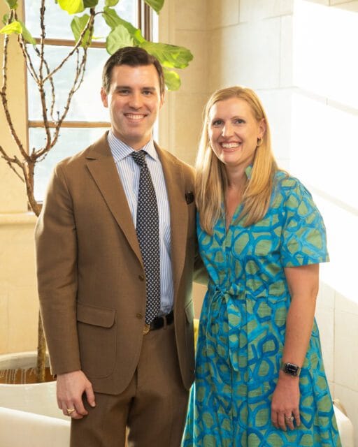 Man in brown suit and woman in blue patterned dress smiling