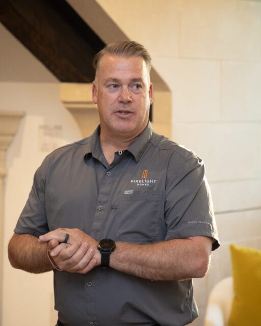 Man in gray shirt with Firelight Homes logo, wearing a watch.