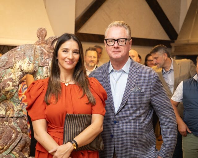 Woman in orange dress and man in blue plaid jacket with glasses