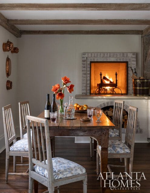 Dining room with rustic wooden table, chairs with floral cushions, and fireplace