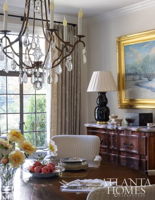 Dining room with crystal chandelier, wooden table, and antique buffet.