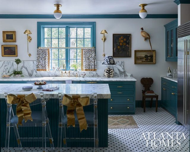 Teal kitchen with marble countertops, island with acrylic stools, and mosaic tile floor.