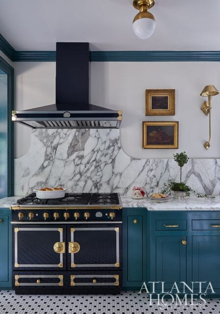 Dark blue range with gold accents, marble backsplash, and teal cabinets.