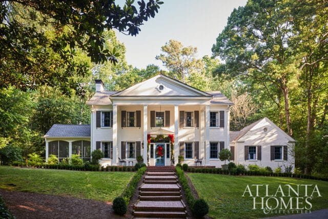White brick house with columns, shutters, and a wreath on the door.