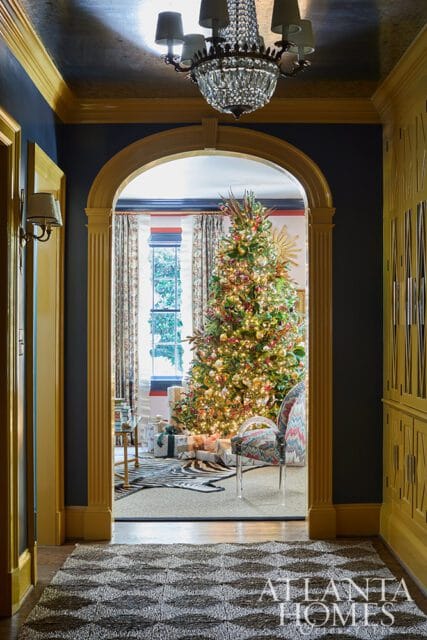 Archway leading to a room with a decorated Christmas tree, gifts, and patterned chair.