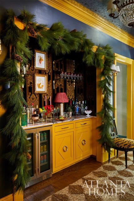 Yellow bar with marble countertop, pine garland, and tiger print wallpaper