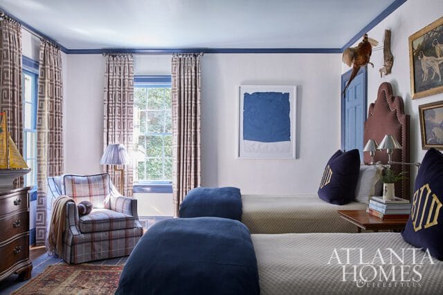 Bedroom with two beds, plaid armchair, and blue abstract art.