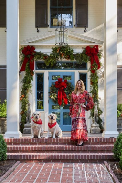 Woman and two dogs on porch with Christmas garland and blue door
