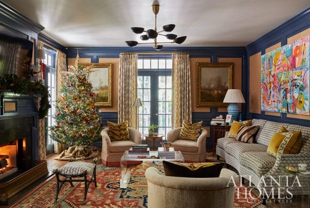 Living room with Christmas tree, fireplace, and abstract art. Dark blue walls, tan grasscloth, and