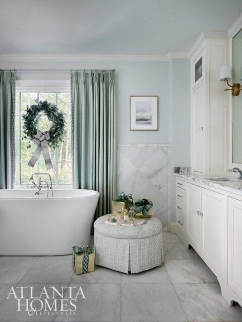 Light blue bathroom with white soaking tub, marble floors, and green curtains.