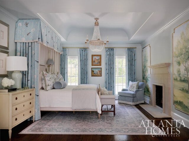 Bedroom with canopy bed, blue floral curtains, crystal chandelier, and fireplace.