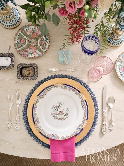 Table setting with floral plates, pink napkin, and ornate silverware.