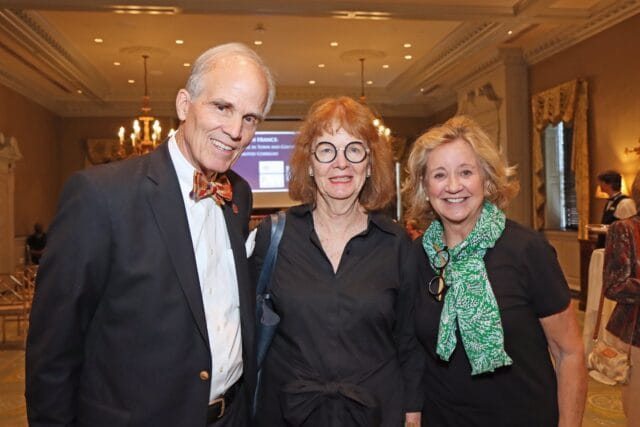 Man in suit and bow tie, woman in black shirt, woman in black shirt with green scarf