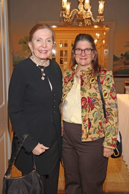 Two women smiling, one in a black jacket and the other in a floral jacket.