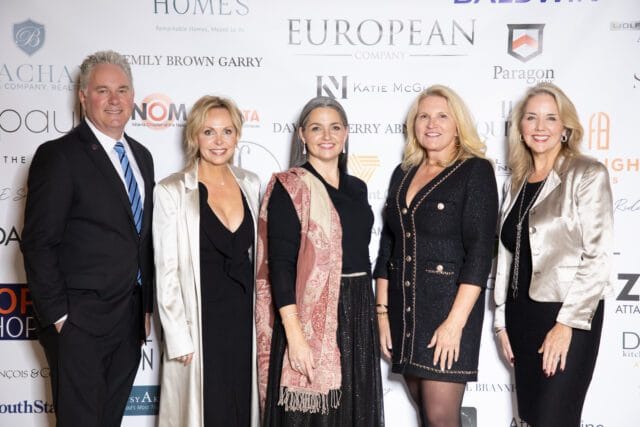 Five people pose for a photo in front of a backdrop with sponsor logos.