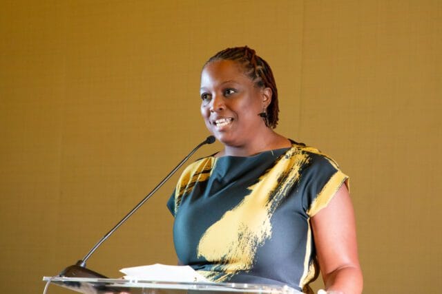 Woman with braided hair speaking at a podium.