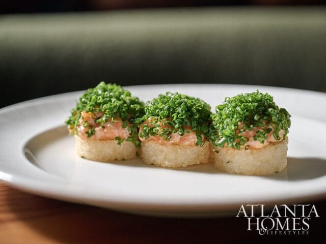Three salmon bites topped with chives on a white plate