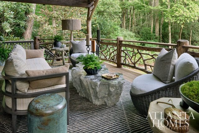 Covered porch with rustic wood railing, stone coffee table, and wicker chairs.