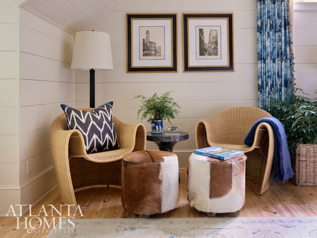 Wicker chairs with cowhide ottomans and blue patterned curtains.